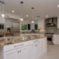 Polished granite countertop with natural gold, black, and cream veining on a large kitchen island with white cabinetry.